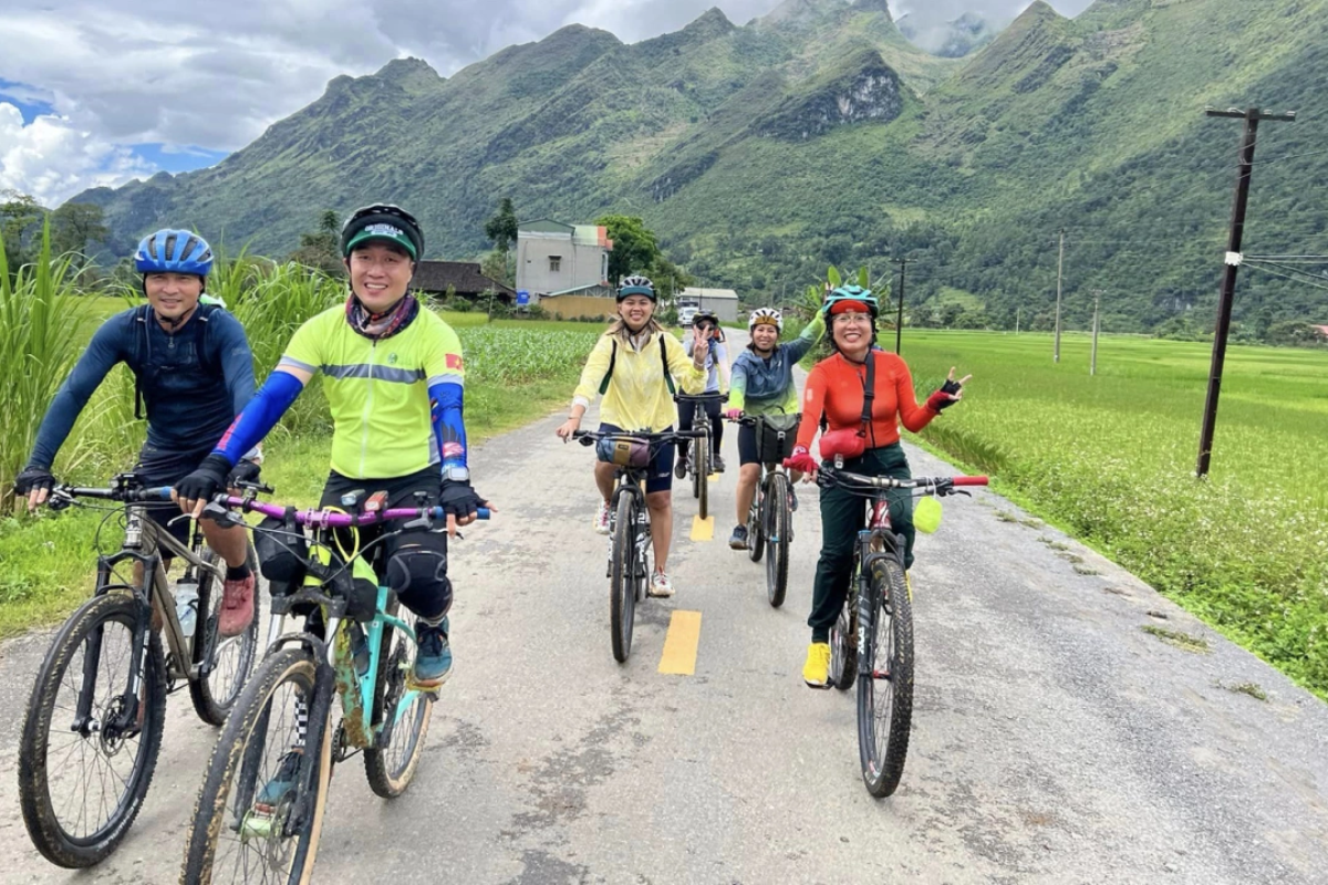 Tourist cycling on a peaceful stretch of Na Tenh Pass surrounded by trees and rice fields